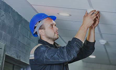 worker-installing-smoke-detector-on-the-ceiling Worker Installing Smoke Detector on the Ceiling
